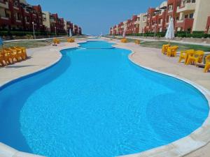 a swimming pool with blue water and yellow chairs at لاسيرينا عيون موسى LaSerinaللعائلات in Ras Sedr