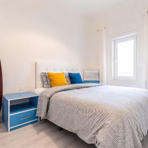 a white bedroom with a bed and a blue nightstand at A Casa do Jamor in Cruz Quebrada