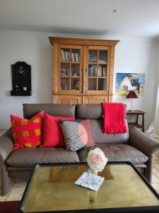 a living room with a brown couch with colorful pillows at Inselhotel Brummers Anneks in Haderslev