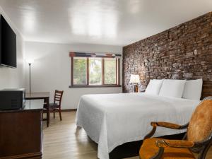a bedroom with a large bed and a brick wall at Avalon Hotel & Conference Center in Chippewa Falls