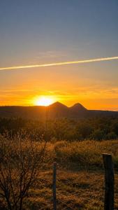 a sunset over a field with a fence and mountains at El Joaquin in Nono