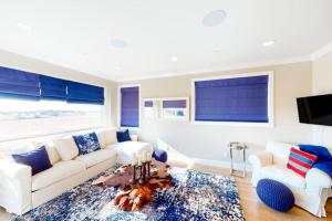 a living room with a white couch and two chairs at Gull Cottage in Seal Beach