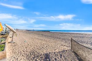 a sandy beach with an umbrella and the ocean at Seashore Dreams B - Upper Unit in Newport Beach