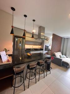 a kitchen with a counter and bar with stools at Apto lindo e completo com piscina em Itajai in Itajaí