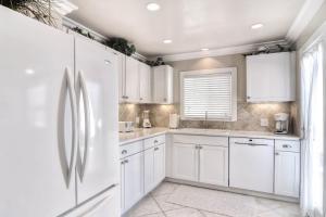 a white kitchen with white cabinets and a refrigerator at San Clemente - Monterey Fourplex in San Clemente