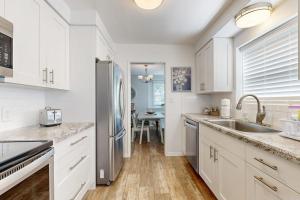 a kitchen with white cabinets and a stainless steel refrigerator at Evening Oasis in Orange +16 photos