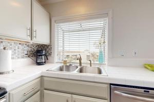 a white kitchen with a sink and a window at Monarch Vista in Dana Point