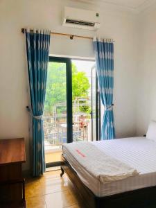 a bedroom with a bed with blue curtains and a window at Thanh Dat 2 Hotel in Vinh