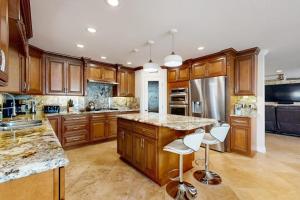 a kitchen with wooden cabinets and a large island with bar stools at Palm Tree Getaway in Newport Beach
