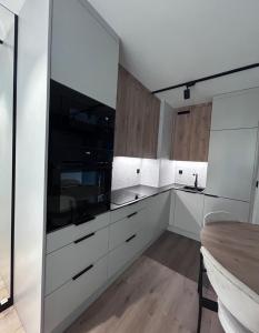 a kitchen with white cabinets and a black microwave at Apartament z Tarasem Parking Smart TV Wi-Fi in Sosnowiec