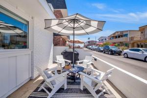 a table and chairs on a balcony with an umbrella at Newport Coastal Compound in Newport Beach