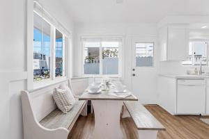 a white kitchen with a table and chairs and windows at Newport Coastal Compound in Newport Beach +27 photos