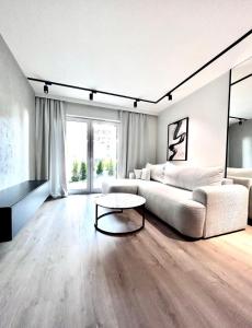 a living room with a white couch and a table at Apartament z Tarasem Parking Smart TV Wi-Fi in Sosnowiec