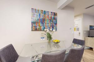 a glass table with chairs and a painting on the wall at On the Doorstep in Anaheim