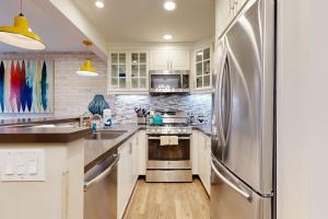 a kitchen with white cabinets and a stainless steel refrigerator at On the Doorstep in Anaheim +20 photos