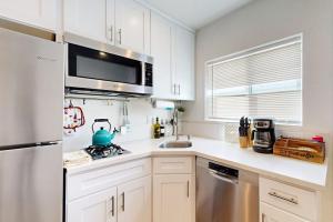 a kitchen with white cabinets and a stainless steel refrigerator at Fair Weather in Newport Beach