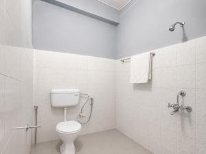 a white bathroom with a toilet and a shower at Hi Hostels Shillong in Shillong