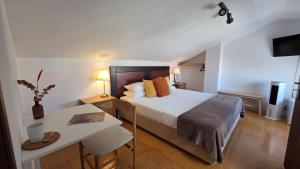 a bedroom with a large bed with a desk at Soleil Bleu in Vila Nova de Milfontes