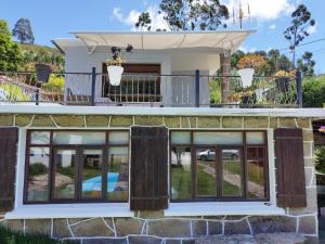 a house with large windows and a balcony at Casa a pié de playa de Cariño Doniños in Ferrol
