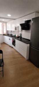 a kitchen with white cabinets and a black refrigerator at Descansa Las Mareas in Santander