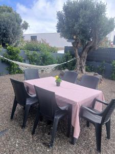 a pink table with black chairs and a tree at Casa das 3 Oliveiras in Porto Santo