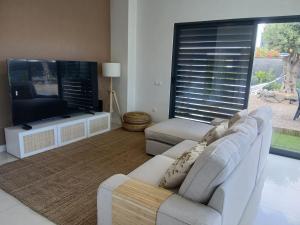 a living room with a white couch and a tv at Casa das 3 Oliveiras in Porto Santo