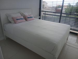 a white bed with two pillows and a window at Casa das 3 Oliveiras in Porto Santo