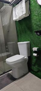 a bathroom with a toilet and a green wall at City suítes hotel in Diamantino