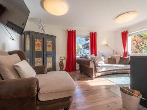 a living room with leather furniture and red curtains at Regenbogenhaus in Mayrhofen