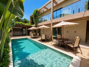 a swimming pool with a table and chairs and umbrellas at LAWAKE House pipa Studios e apartamentos nomads in Pipa