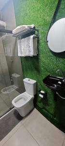 a green bathroom with a toilet and a sink at City suítes hotel in Diamantino