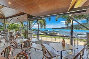 a restaurant with tables and chairs and a view of the ocean at Club Airlie in Airlie Beach
