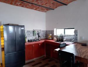 a kitchen with a black refrigerator and a table at Off-grid mountain house with a view La Manchoza in Tapalpa +12 photos