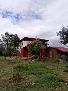 a red and white house in a field at Off-grid mountain house with a view La Manchoza in Tapalpa