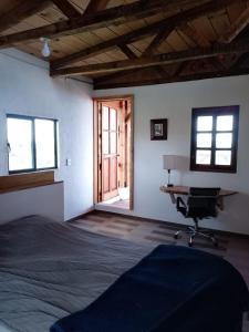 a bedroom with a bed and a desk and windows at Off-grid mountain house with a view La Manchoza in Tapalpa