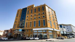 a tall building with cars parked in front of it at Mirada Purple Najran Hotel in Najran