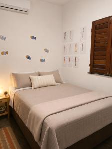 a bedroom with a bed with a window and pictures on the wall at Tigre Beach House in Trairi
