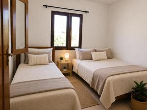 two beds in a room with a window at Tigre Beach House in Trairi