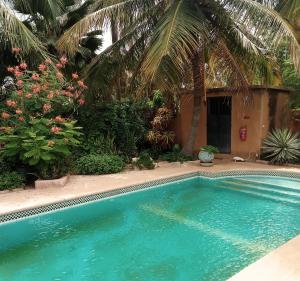 a swimming pool in front of a house with palm trees at VILLA Alia in Nianing