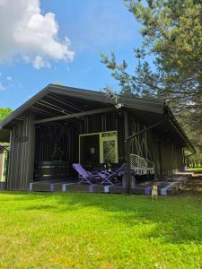 a black house with purple chairs and a yard at VIP Yellow dream house Sodyba Geras geltona žalia raudona violetinė in Anykščiai