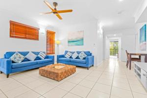 a living room with blue couches and a ceiling fan at Bluewater Haven - Sweeping Lagoon Views with Pool in Trinity Beach