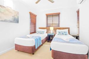 two beds in a room with white walls and windows at Bluewater Haven - Sweeping Lagoon Views with Pool in Trinity Beach +4 photos