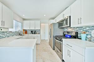 a kitchen with white cabinets and white counter tops at Pier View Paradise in San Clemente