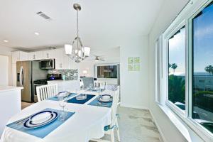 a dining room with a white table and a kitchen at Pier View Paradise in San Clemente