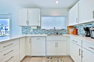a white kitchen with white cabinets and a sink at Pier View Paradise in San Clemente +14 photos