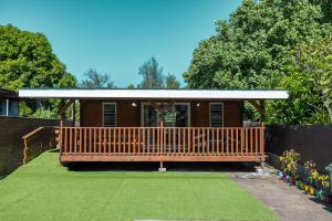 a house with a large wooden deck with a yard at Fare AGT Moorea in Afareaitu