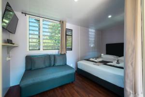 a bedroom with a bed and a couch and a window at Fare AGT Moorea in Afareaitu