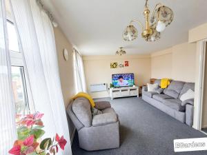 a living room with two couches and a tv at E Gardens Apartment in Nottingham