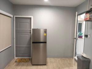 a stainless steel refrigerator in a room with a door at Small home in Ban Khlong Hok Wa