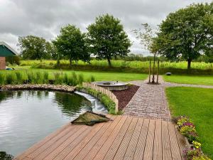 a garden with a pond and a wooden deck at Ferienwohnung Marita 35681 in Uplengen